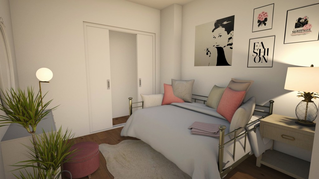 Entering in to the bedroom now, this small space has been transformed into a cozy feminine oasis. Across from you against the wall on the right a golden day bed is centered on the wall. It's covered in rose, blush, gold, and cream pillows and bedding. Above the bed a painting of Audrey Hepburn is paired with vintage black and pink fashion style artwork. To the right a small table sits with a golden pineapple lamp giving the space a warm glow. A fluffy white rug extends from underneath the bed reaching out to a vanity that sits across from it.