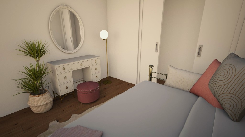 Looking now from on the bed you can see the art deco style gold and white vanity. It is paired with a rose ottoman. To the right a lamp offers some additional light. To the left a yucca plant sits in a woven basket bringing some green into the space.