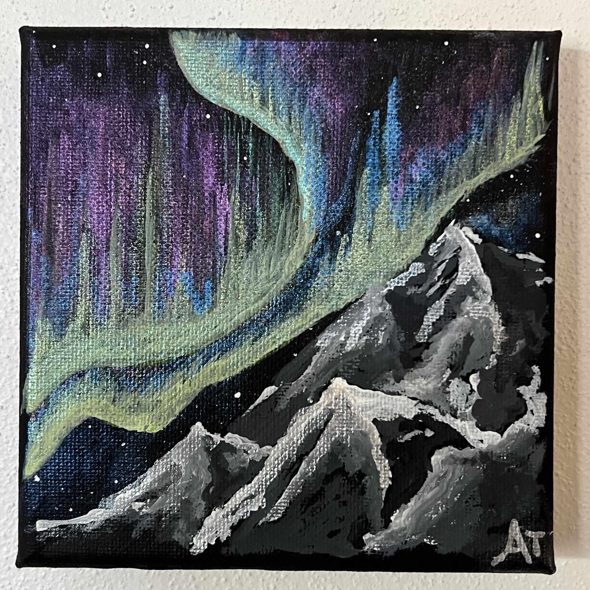 a vivid green and blue and pink aurora borealis dancing in the night sky above snow covered mountains