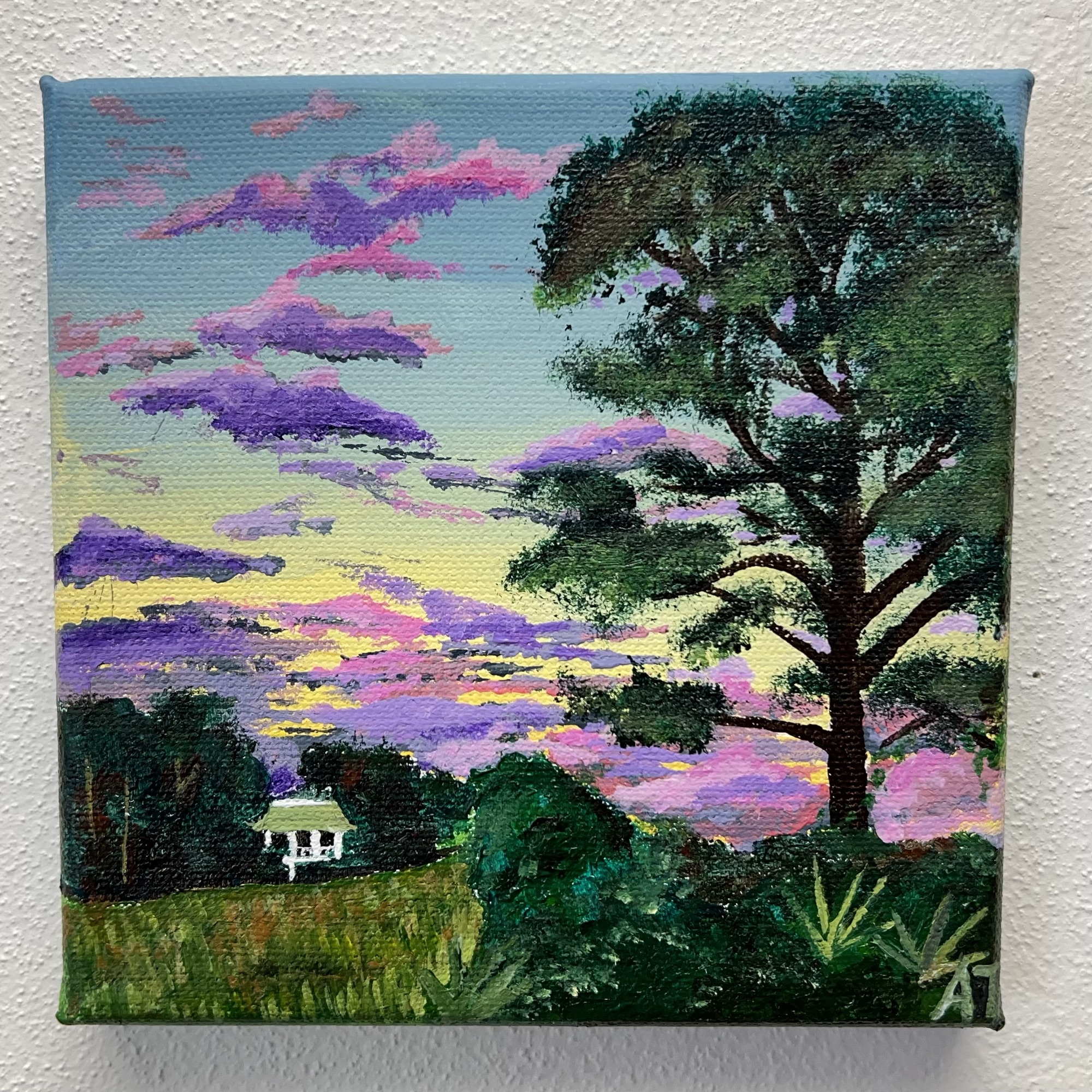 a tall loblolly pine stands tall to the right overlooking a green marshy grass, across sits a peninsula full of trees where a small white house is perched. The sky striped with deep purple and lavender clouds with hints of pink.
