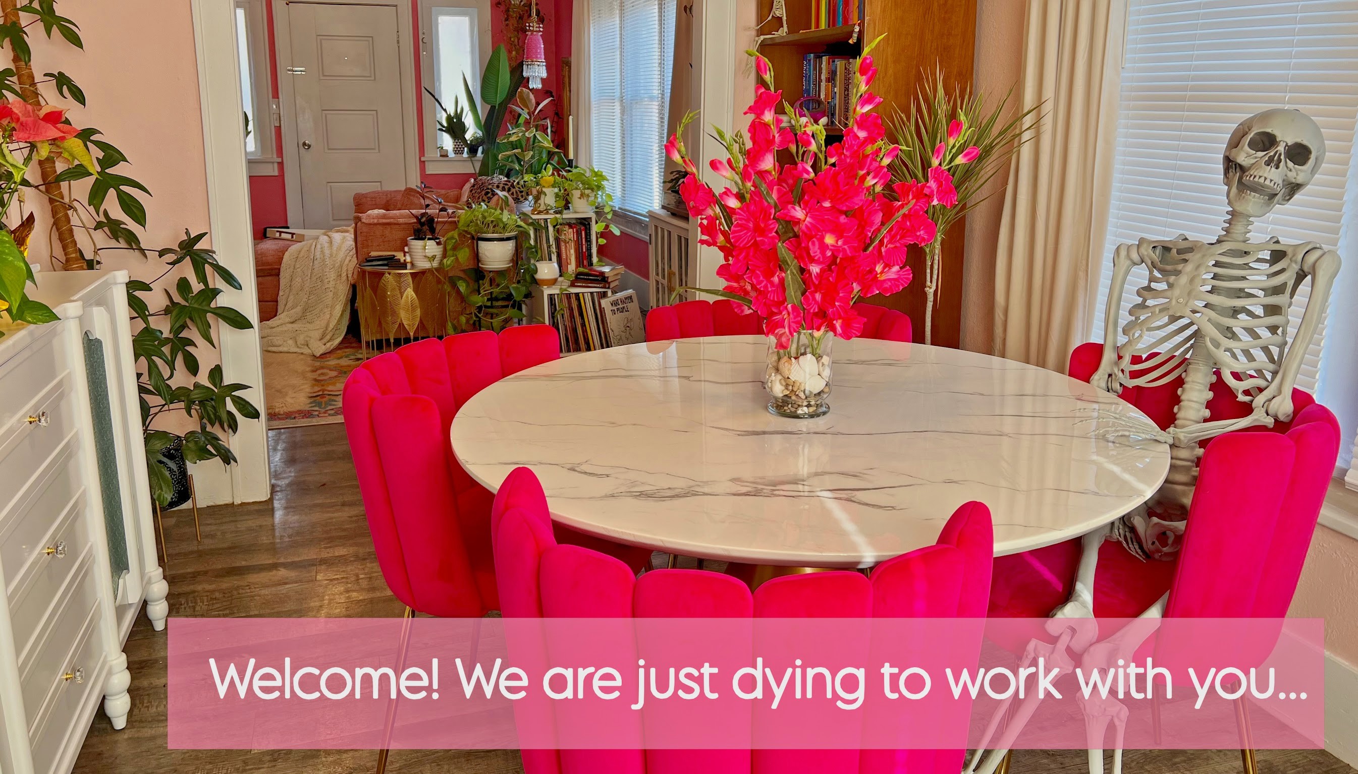 edgar my skeleton sits on a pink dining chair around my dining table arm propped up on the back of the chair joyfully looking your way.