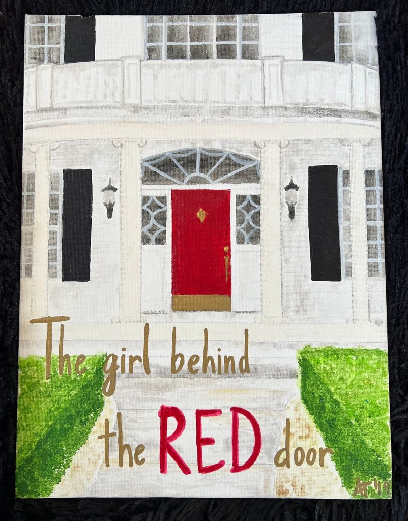 A vertical canvas panel featuring a white colonial home with black shudders around the windows that frame the red door in the center. Green hedges line the walkway up to the home where the phrase "the girl behind the RED door" is written 